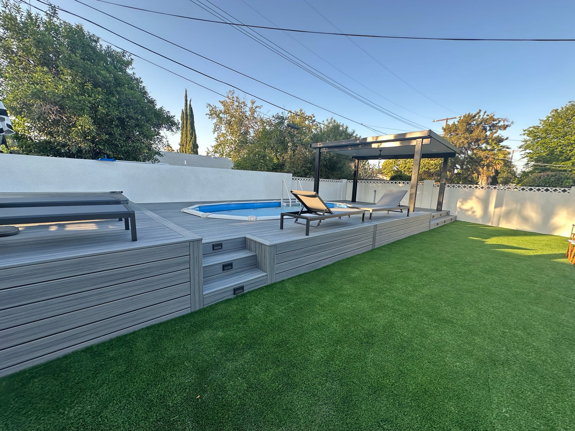 Backyard remodeling project featuring Trex decking, covered patio structure, pool and artificial turf installation.
