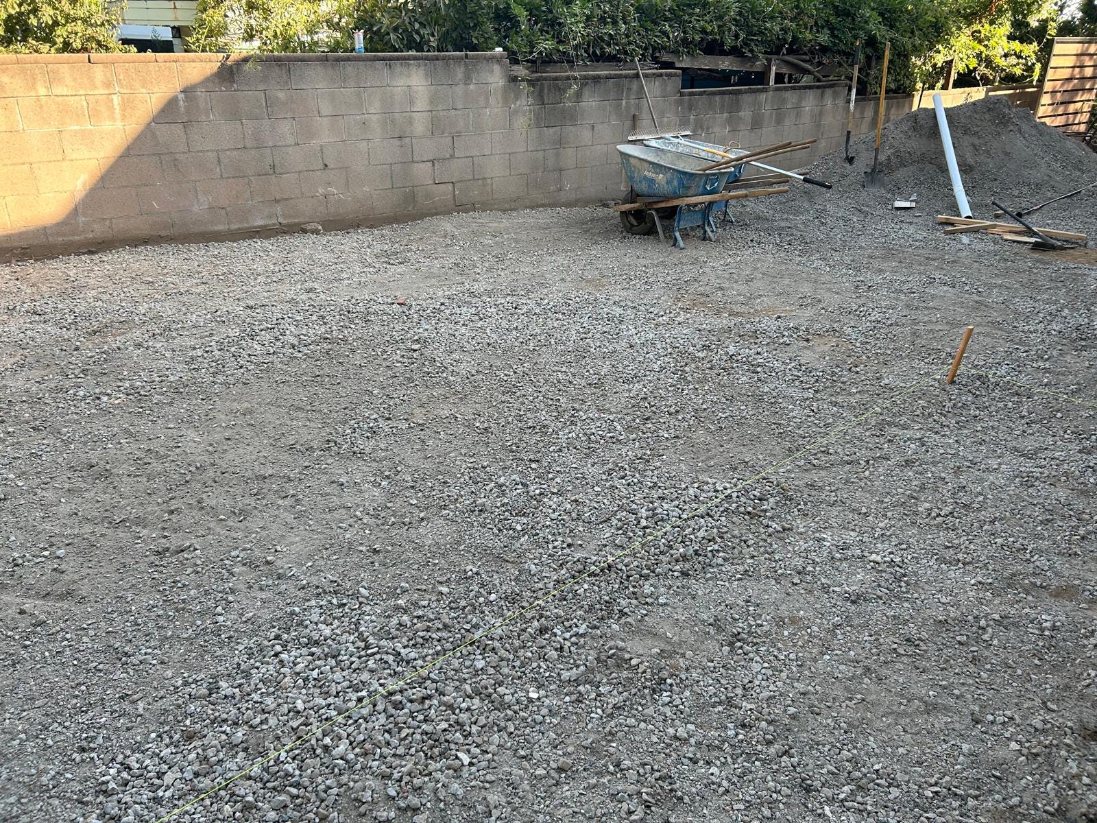 Installing sand bedding for paver alignment in backyard
