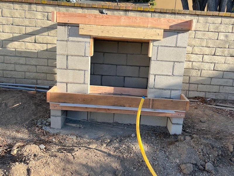 Custom outdoor fireplace frame construction in Orange CA with concrete block foundation and structural build process