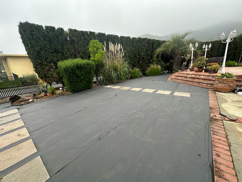 Weed barrier installation during backyard remodeling project.